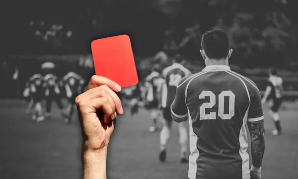 a black and white image of a men's rugby team playing on the field, with an overlaid hand holding a red card up
