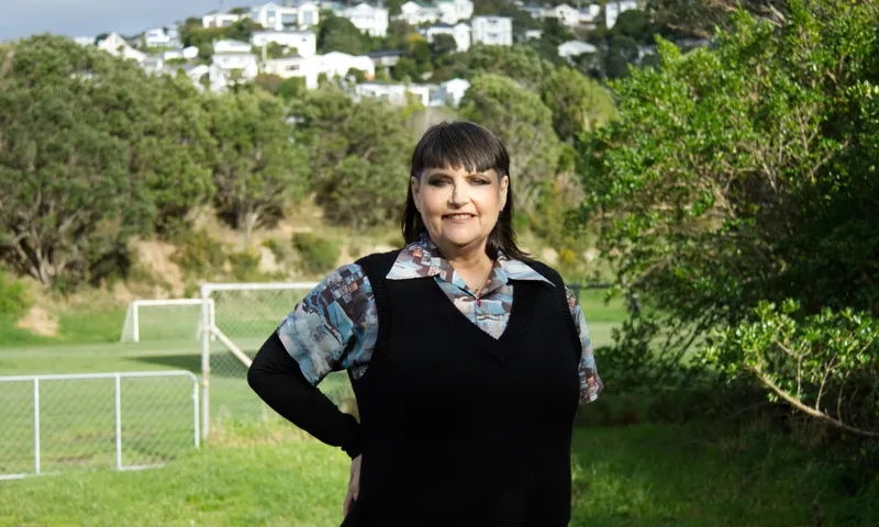 The author pip adam standing in a field in wellington and smiling.
