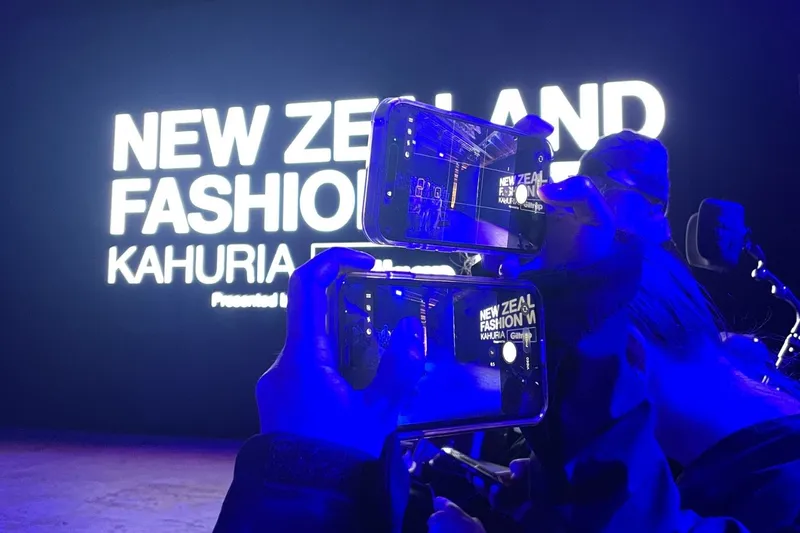 A front row guest uses two phones at once.