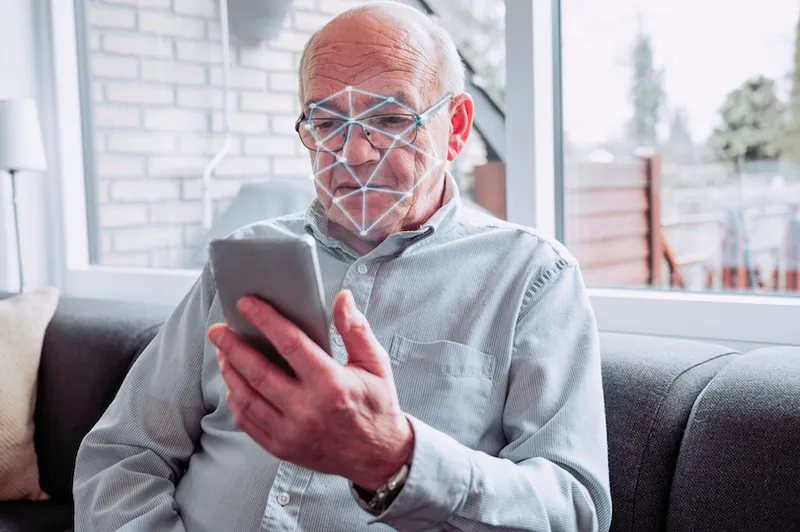 Facial recognition software scans the face of senior man holding smart phone