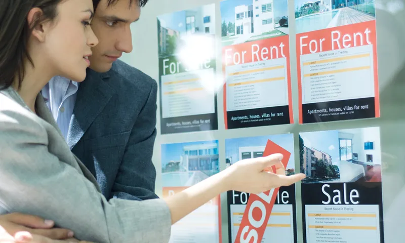 Couple looking at properties in window of real estate agency