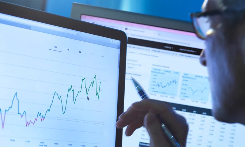 Financial services, stock analyst researching share price data of a company on the computer
