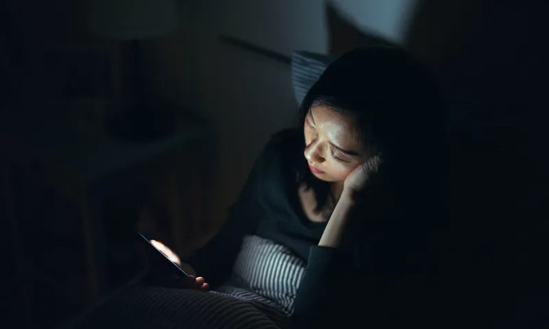 Tired woman fell asleep while using smartphone in bed at night