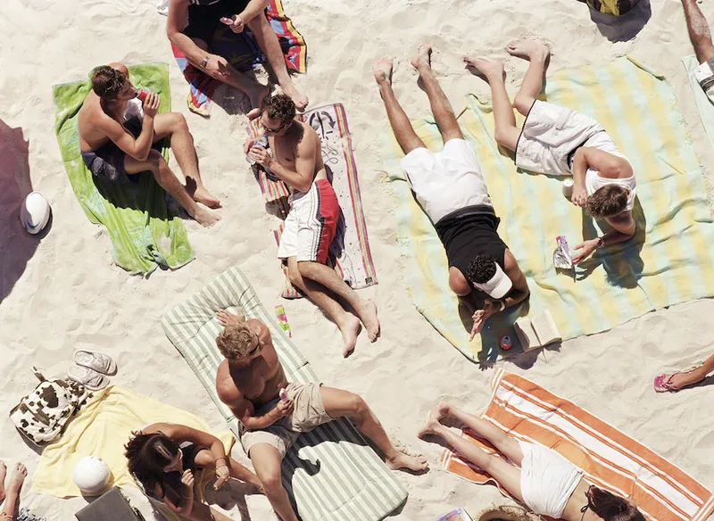 Group of people eating and drinking on beach, overhead view