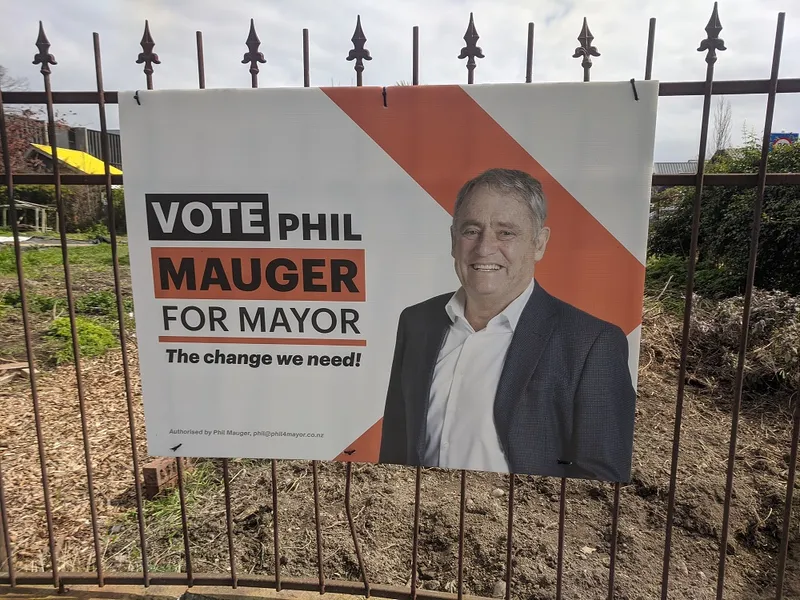 An election billboard with phil major (white man in suit) on it. background is a fence