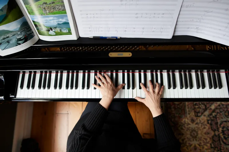 A top-down photograph of composer Victoria Kelly's hands playing a grand piano