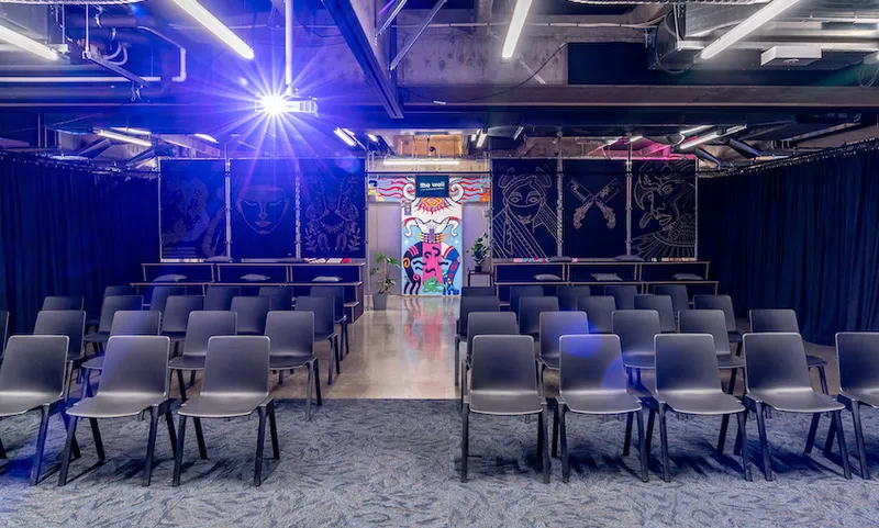 A room with several rows of chairs, a projector and a colourful mural in the background.
