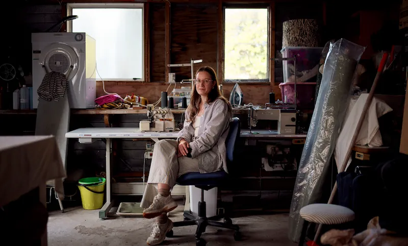 Whitney Barnes sits in the centre of her garage surrounded by sewing machinery and fabrics.