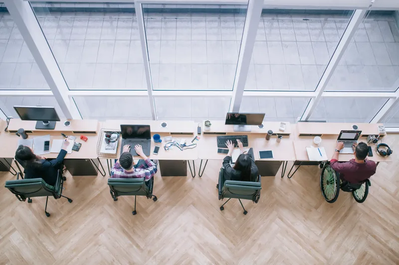 directly above high angle view Indian Businessman in wheelchair working with his colleague in creative office