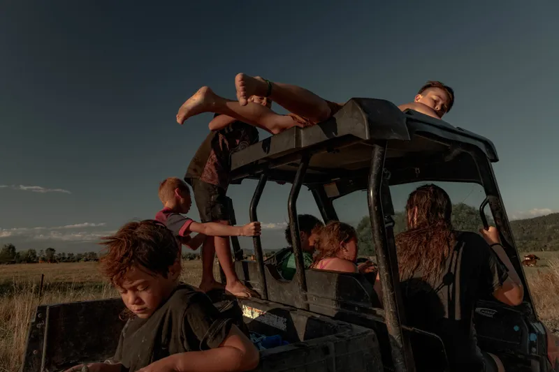 a group of children climbing on the roof of an all terrain vehicle on the beach