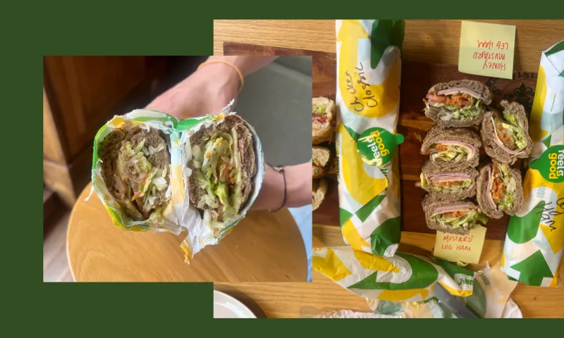 A close-up of a hand holding a halved sandwich with visible veggies and meat, overlaid on an image of various wrapped and sliced sandwiches with yellow and green Subway branding on a wooden surface.