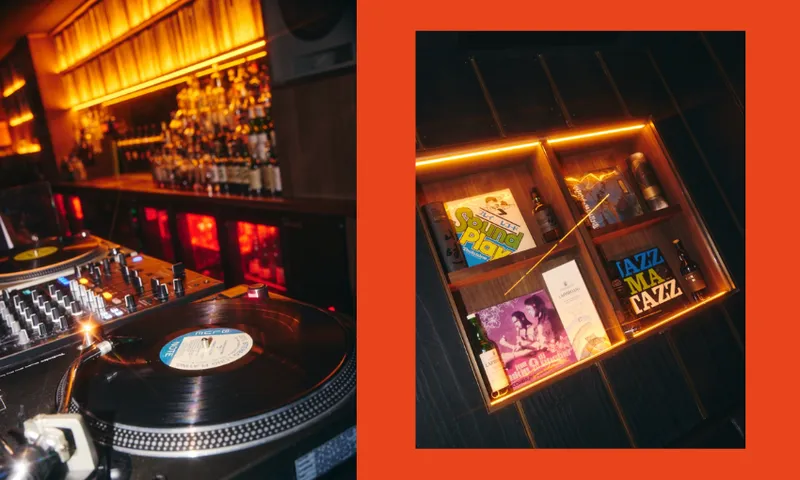 A dimly lit bar with a DJ turntable and vinyl record on the left, and a glowing wooden shelf displaying vinyl records and small bottles on the right, framed by a bold orange border.