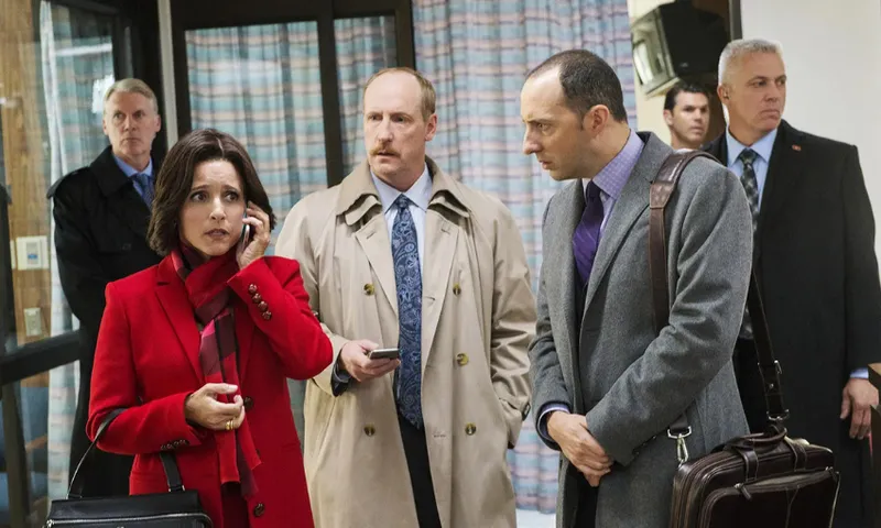 five people in suits stand around looking concerned while one of them, a woman in a red coat, speaks on the phone
