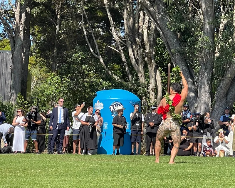 man performing wera, with people in background taking photos