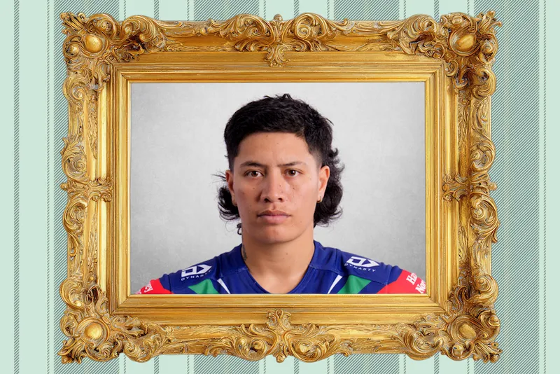 A young person with short dark hair wears a blue sports jersey, looking serious inside an ornate gold picture frame on a light striped background.