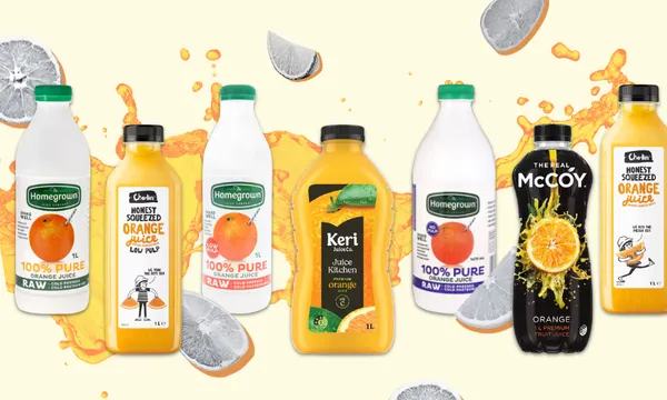 A selection of seven orange juice bottles and cartons, featuring various brands and labels, with splashes of juice and slices of orange and lemon on a light background.
