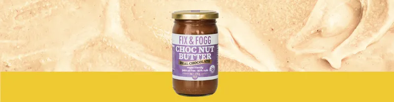 A jar of Fix & Fogg Choc Nut Butter sits against a creamy, chocolatey background with a yellow stripe at the bottom.