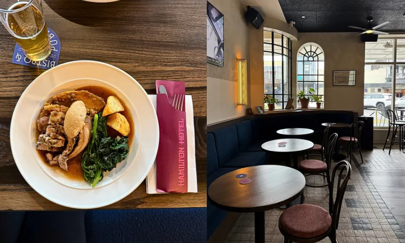 A plate with roast meat, potatoes, greens, and gravy sits on a table with a beer and napkin labeled “Hamilton Hotel.” The image also shows a cozy, empty café with wooden tables and large windows.
