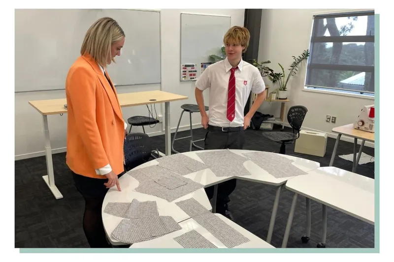 Cooper and Casey stand over a table looking at pieces of fabric.