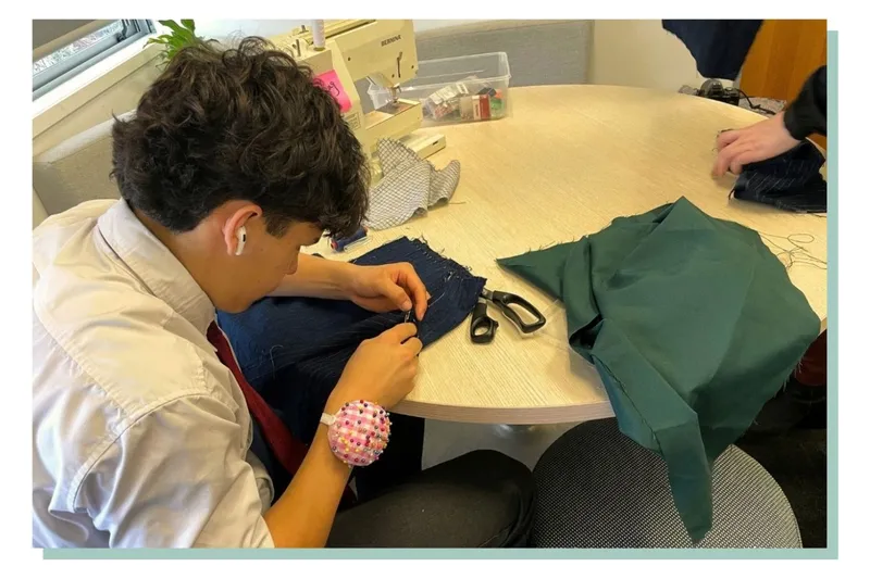 Blas puts pins in fabric.
