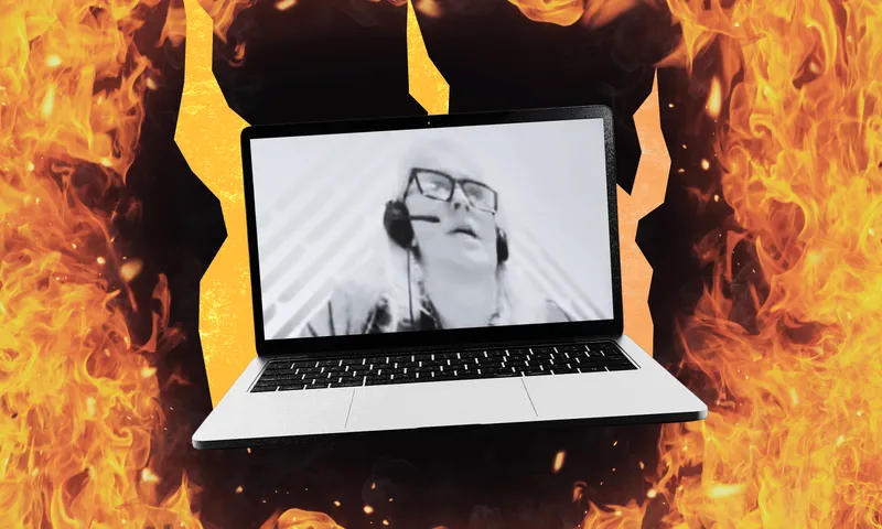 A laptop screen displaying a black and white image of a woman wearing glasses and a headset, against a background of flames