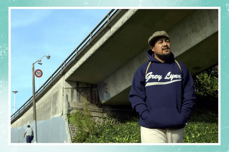 Hip hop star Che Fu, wearing a Grey Lynn hoodie, stands in front of a motorway overpass in Auckland, 2002, the night after his album Navigator won five awards