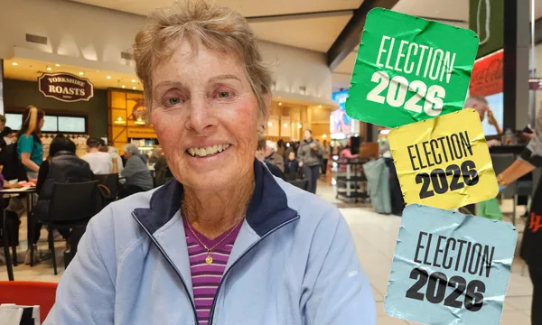 Mary Tahiwi, a 74-year-old retired nurse with brown hair and a blue jacket sits in a busy mall food court.