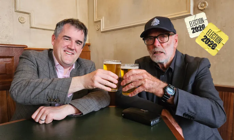 Chris Bishop, a middle-aged National minister with brown greying hair and Wayne Brown, an elderly man with grey hair, clink their full beer glasses together.