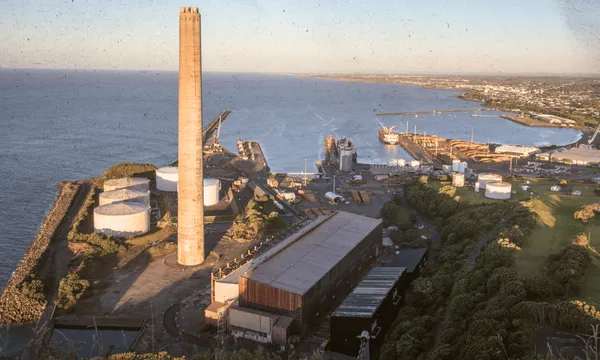  High angle view of coastal industrial area with a tall chimney, storage tanks, and a harbor at sunset,New Plymouth,New Zealand 