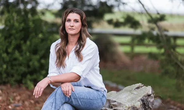 A woman sitting on a log outside