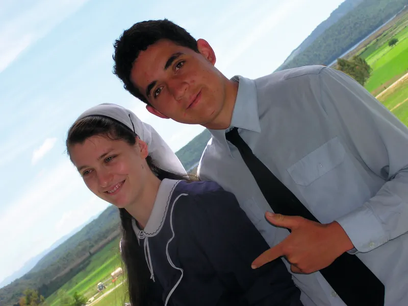 A woman in a smock and headscarf and a man in shirt and tie