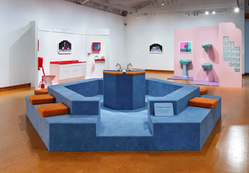 A blue carpeted conversation pit in a gallery setting