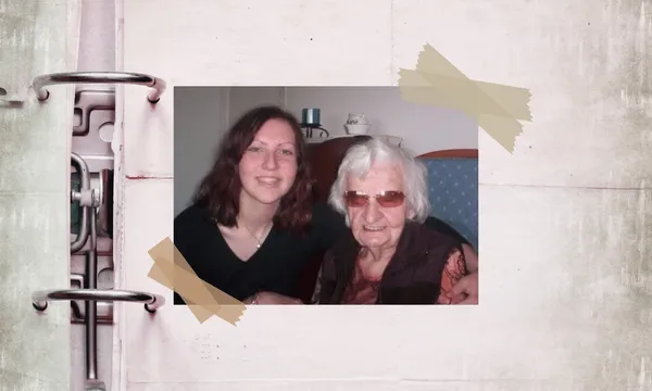 a young woman with curly brown hair sits next to an elderly woman with short white hair and tinted glasses