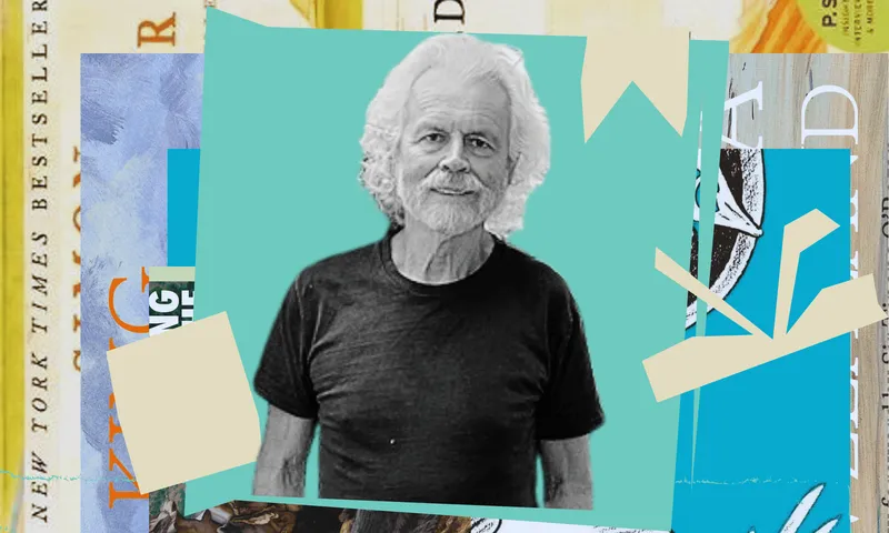 A black and white picture of Richard Wolfe who is an older man with white hair. He's wearing a black t-shirt. Behind him is a collage of coloured shapes.