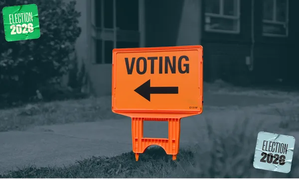 An orange sign saying "voting" with an arrow pointing left, against a black and white background, with stickers in either corner of the image saying "election 2026".