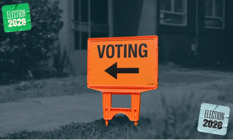 An orange sign saying "voting" with an arrow pointing left, against a black and white background, with stickers in either corner of the image saying "election 2026".